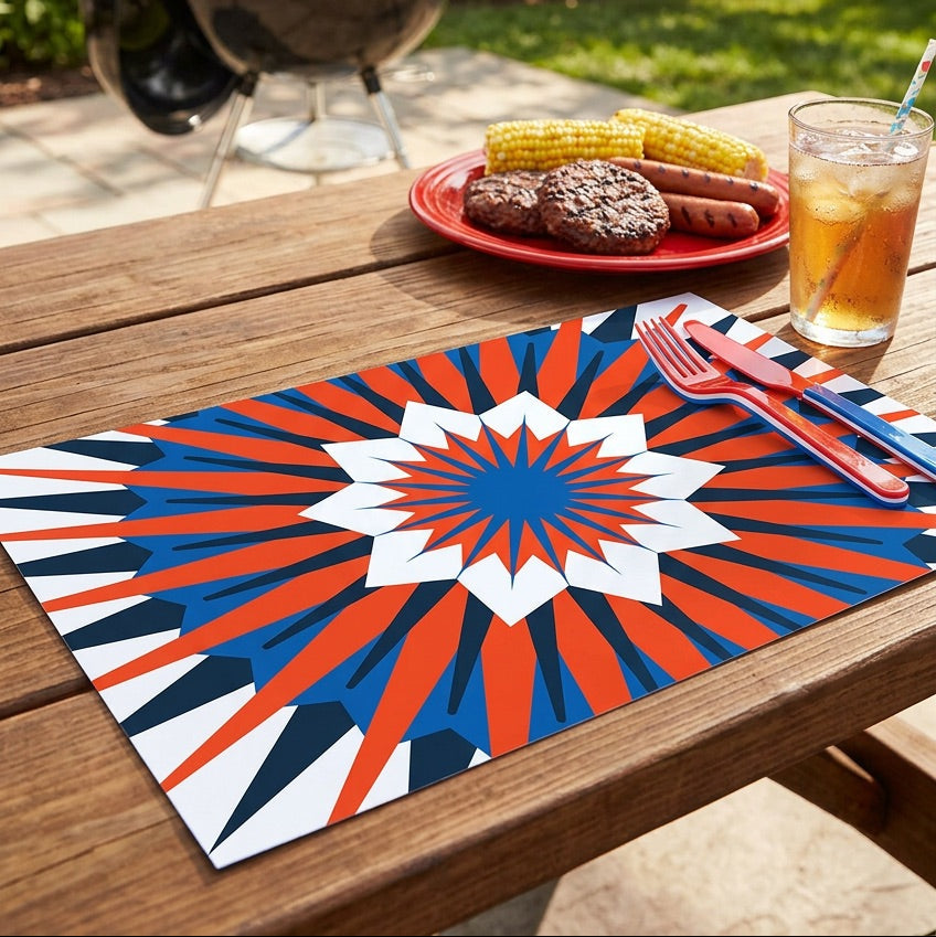 Outdoor setting with a grill, food on a plate, and a drink on a table with a patriotic paper placemat.