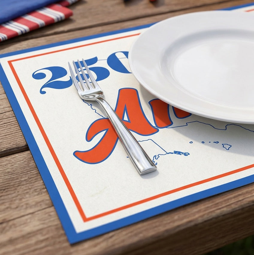 Paper placemat with a patriotic design on a wooden table with a plate and fork.