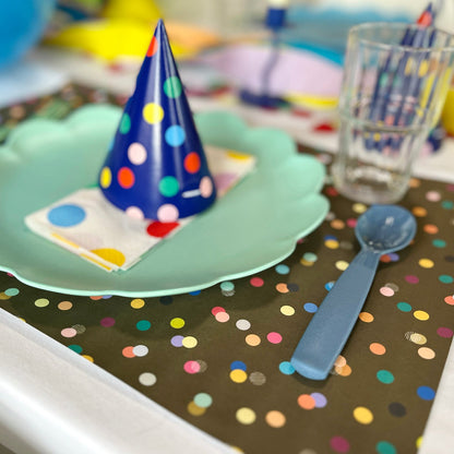 Children's party table setting with a blue polka dot party hat on a green plate.