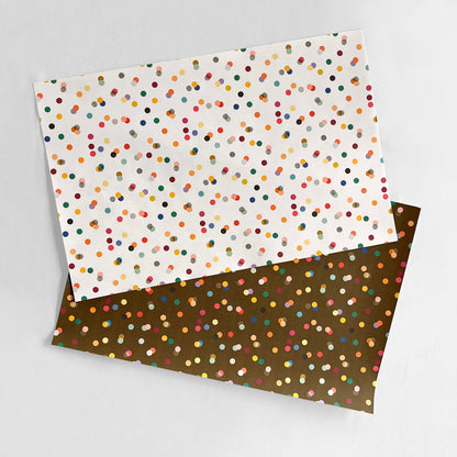 Two sheets of paper with multicolored dot patterns on a gray background