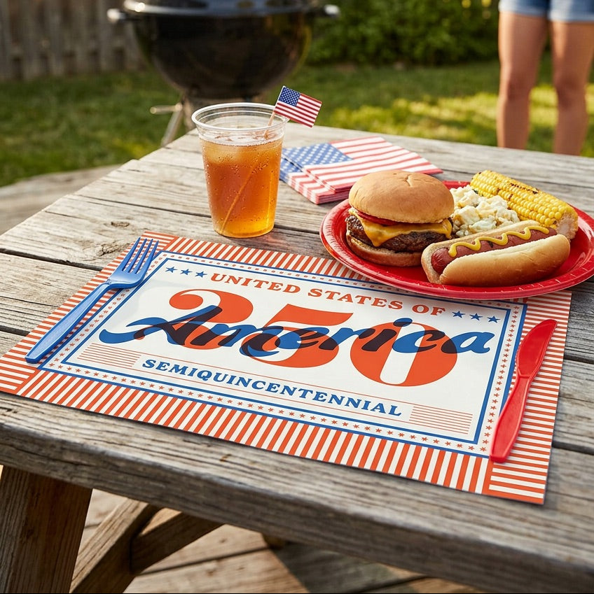 Outdoor setting with a grill, table, and food on a 'United States of America' paper placemat.