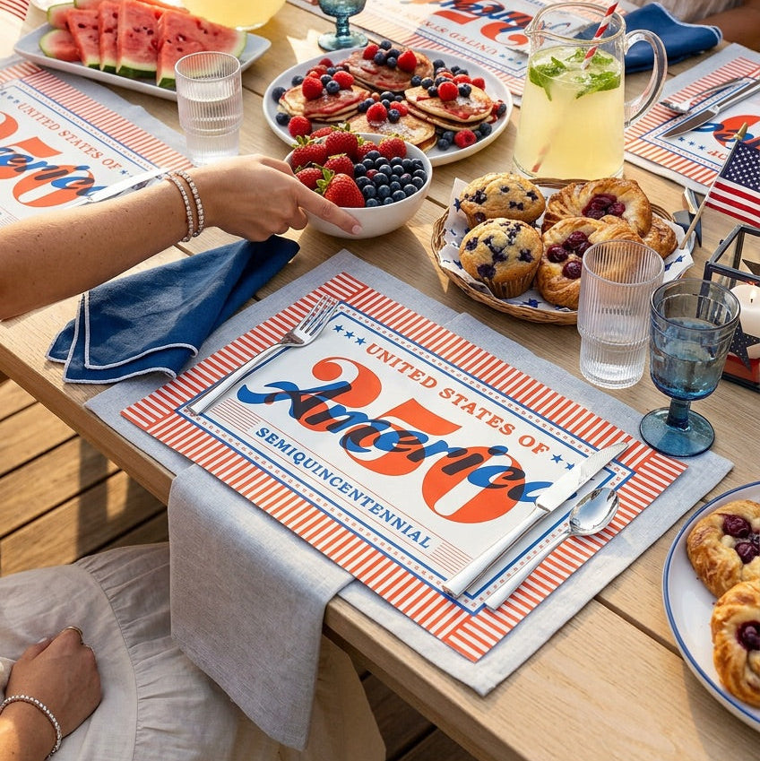 People enjoying a picnic with food and drinks on patriotic paper placemats.