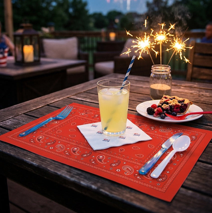 Outdoor setting with a table set for a meal, drinks, and fireworks in the background.