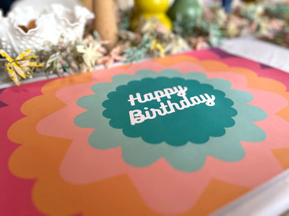 Colorful birthday paper placemat with 'Happy Birthday' text on a blurred background