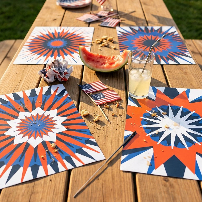 Outdoor table setting with red, white, and blue decorations, including paper placemats and small American flags.