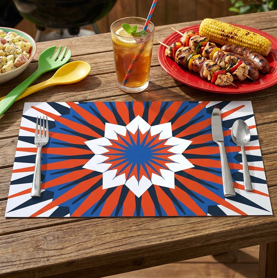 Outdoor setting with a grill, tableware, and food on a patriotic paper placemat.