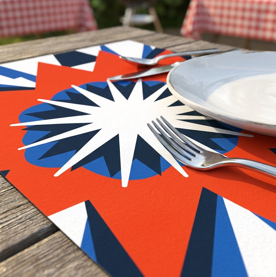 Colorful geometric paper placemat with cutlery on a wooden table outdoors.