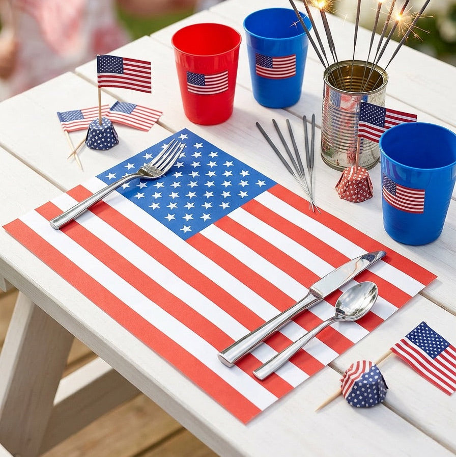 Table setting with American flag paper placemats, cups, and decorations on a white table.