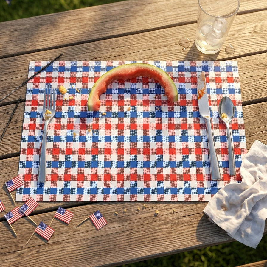 Outdoor setting with a red, white, and blue checkered paper placemat on a wooden table, featuring a watermelon slice and American flags.