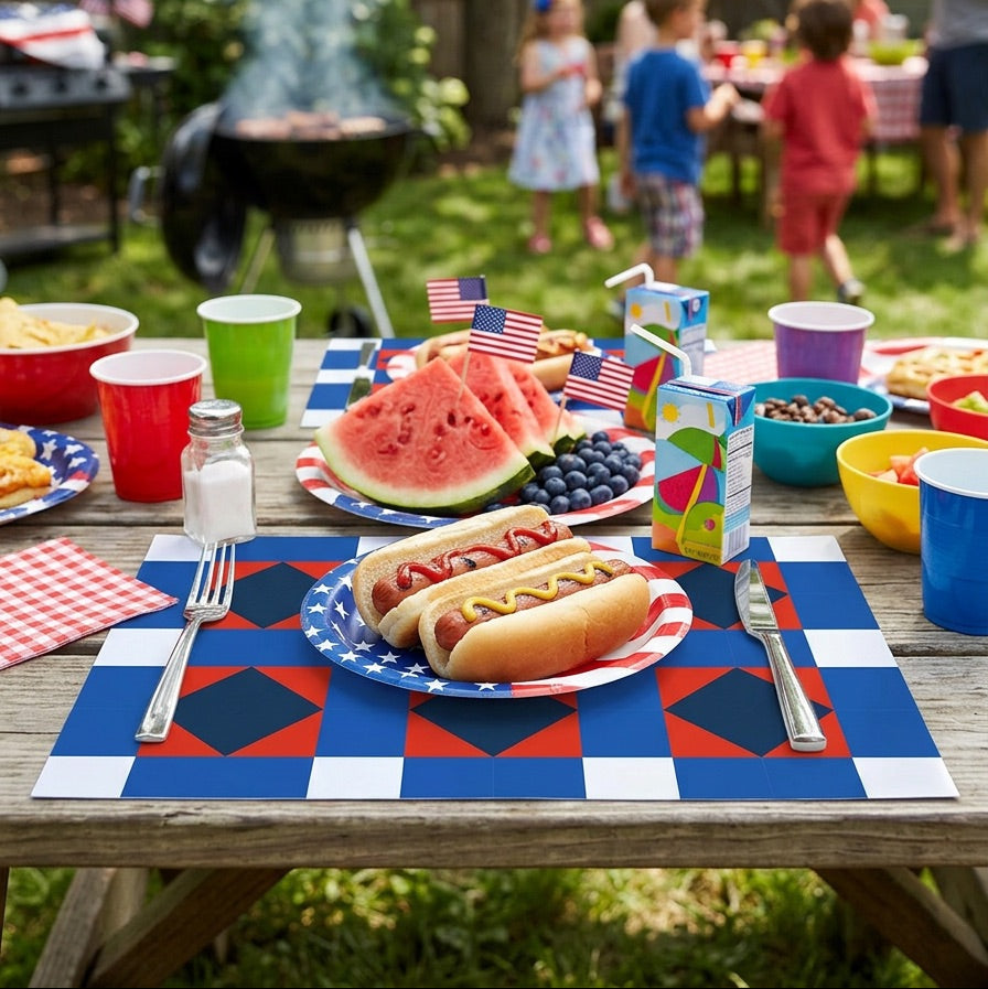 Outdoor picnic scene with hot dogs, watermelon, and food on a paper placemat, children in a backyard setting.