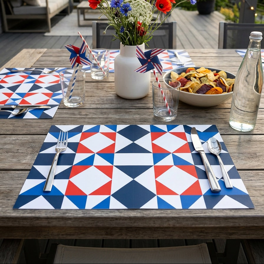 Outdoor table setting with patriotic decor, including paper placemats, flowers, and snacks.