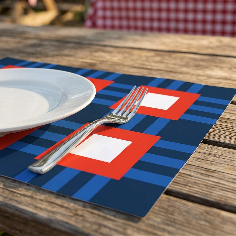 Blue and red checkered paper placemat with a white plate and fork on a wooden table outdoors.