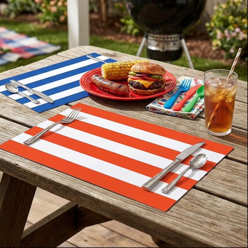 Outdoor setting with a grill, food on a plate, and drinks on a wooden table with striped paper placemats.