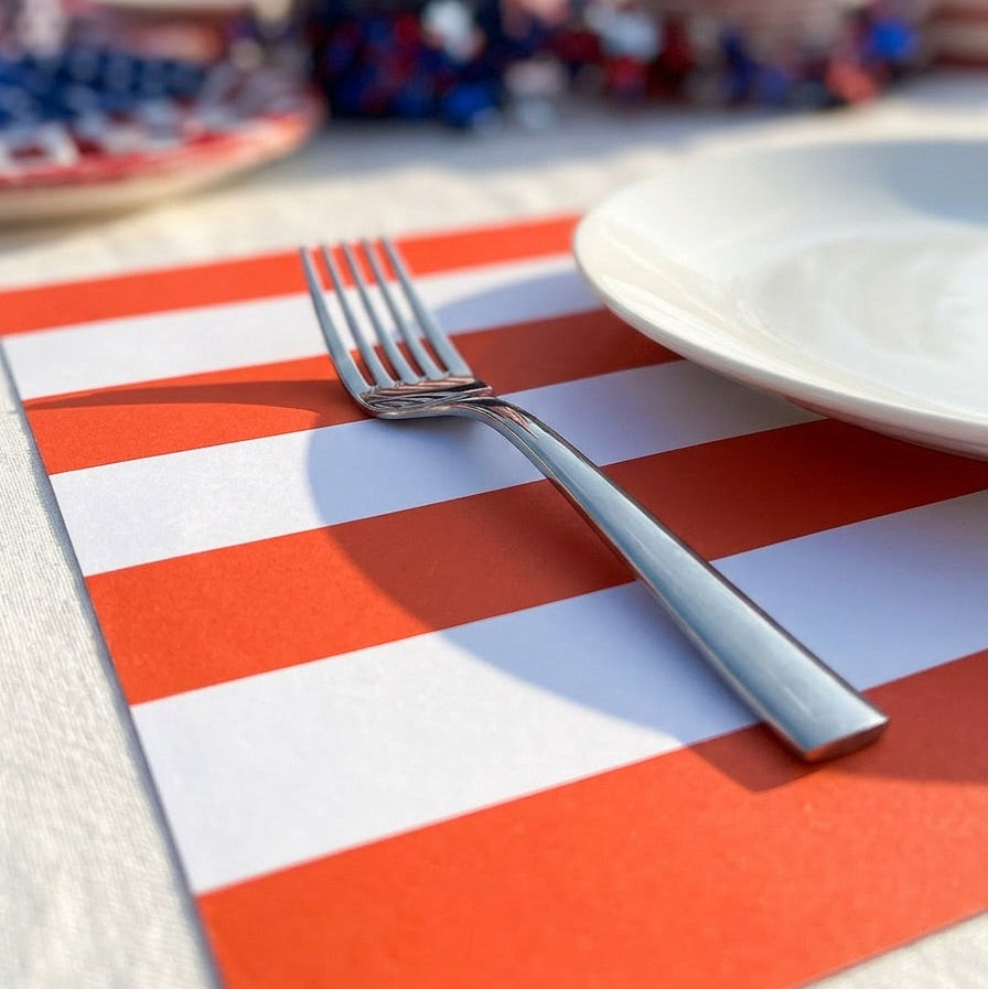 Table setting with a red and white striped paper placemat, fork, and blurred background