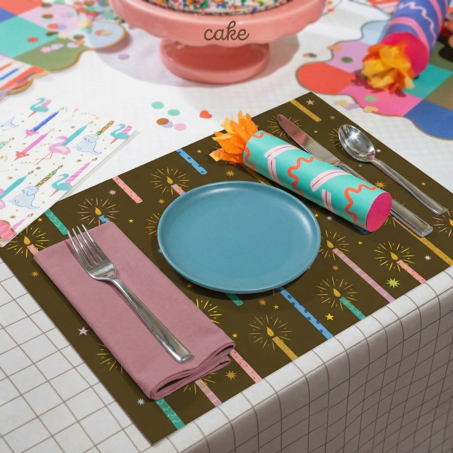 Colorful table setting with a blue plate, pink napkin, and decorative paper placemat.