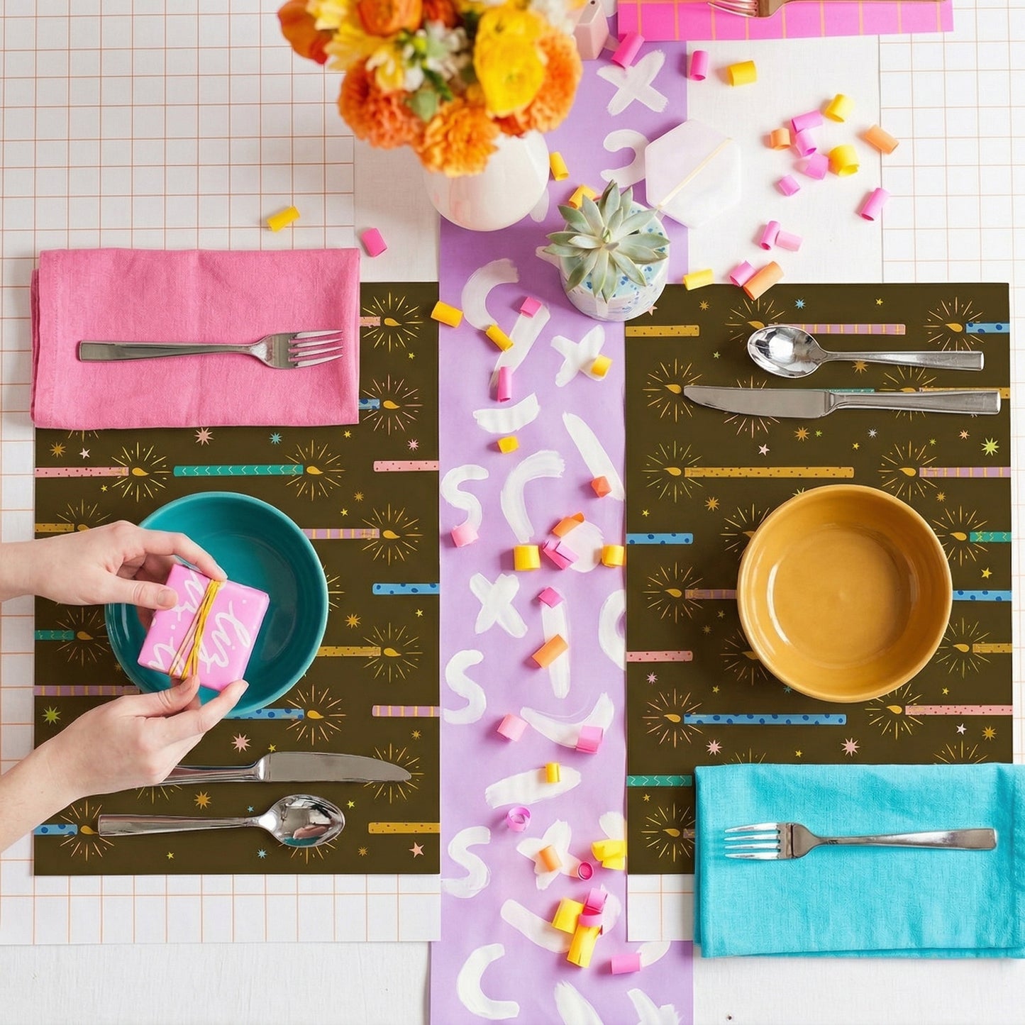 Colorful placemats with cutlery and bowls on a checkered tablecloth.