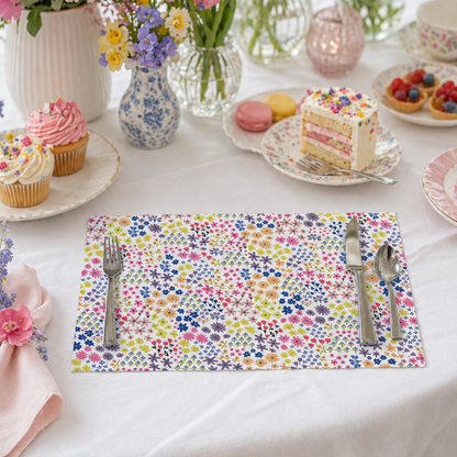Table setting with colorful flowers, desserts, and a floral paper placemat.