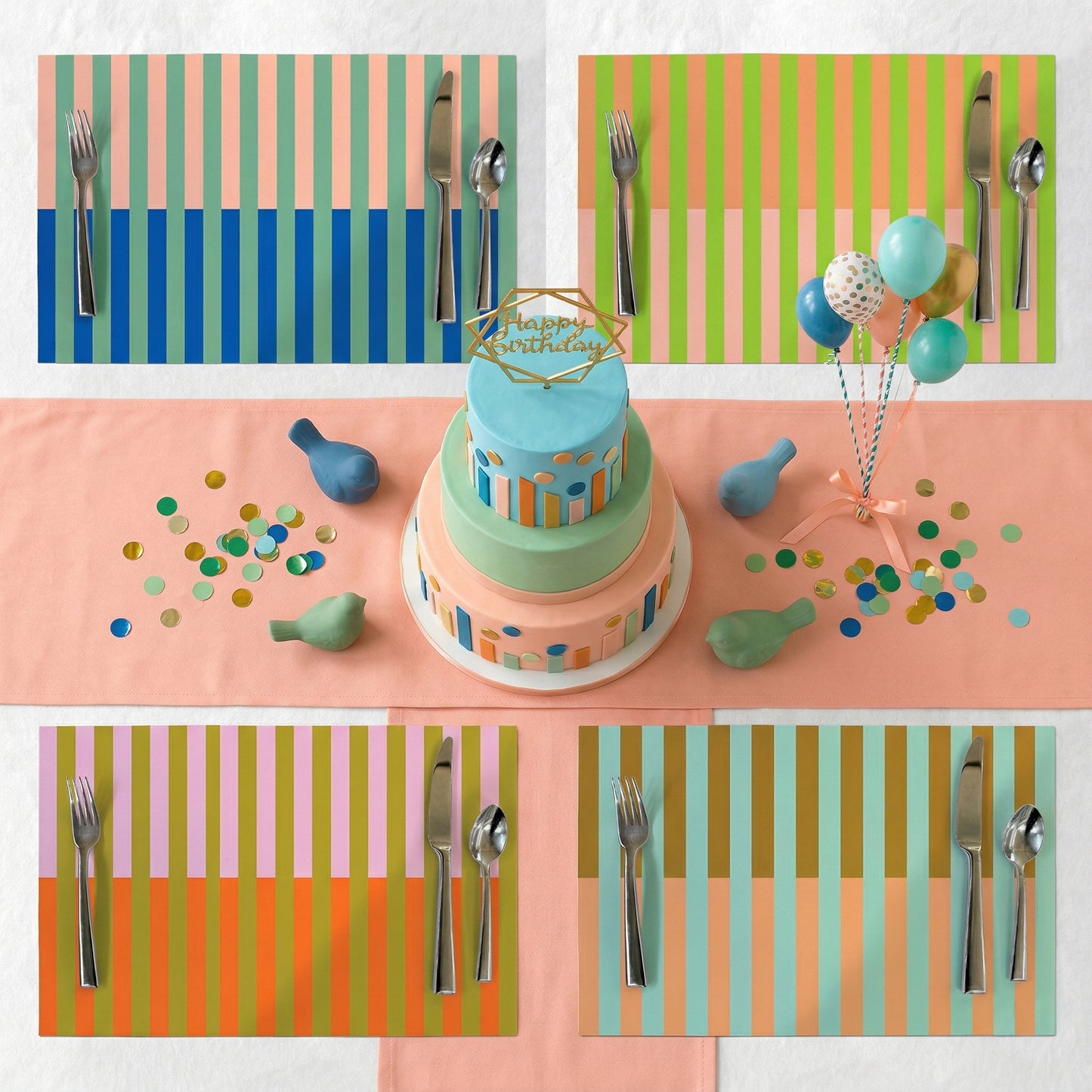 Colorful table setting with a birthday cake, balloons, and striped paper placemats.