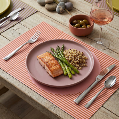 Modern striped paper placemat on a wood table set up for a modern dinner party.