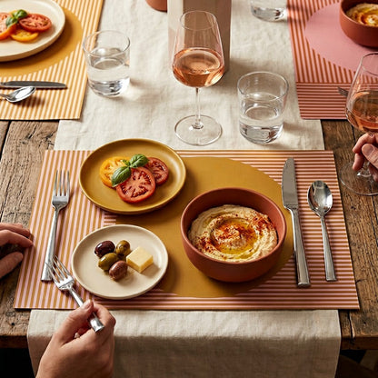 Modern striped paper placemat on a wood table set up for an outdoor brunch. 