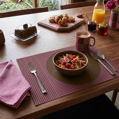 Modern striped paper placemat on a wood table with breakfast in a bowl. 
