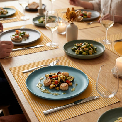 Modern striped paper placemat on a wood table set up for a dinner party. 
