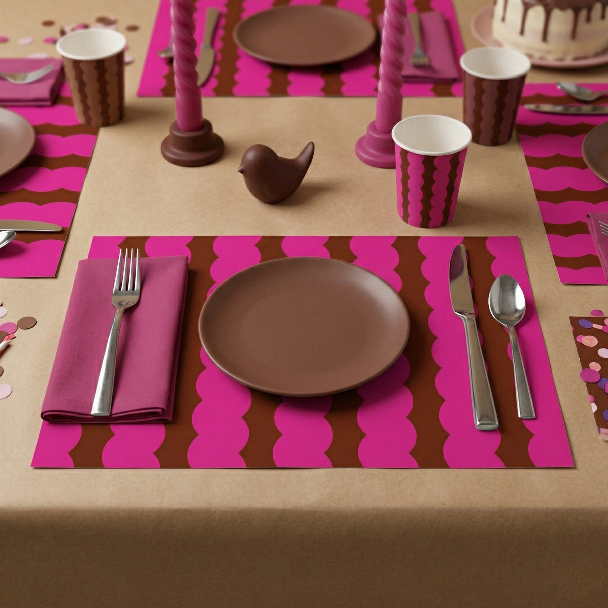 Table setting with pink and brown placemats, plates, and cutlery on a matching tablecloth.