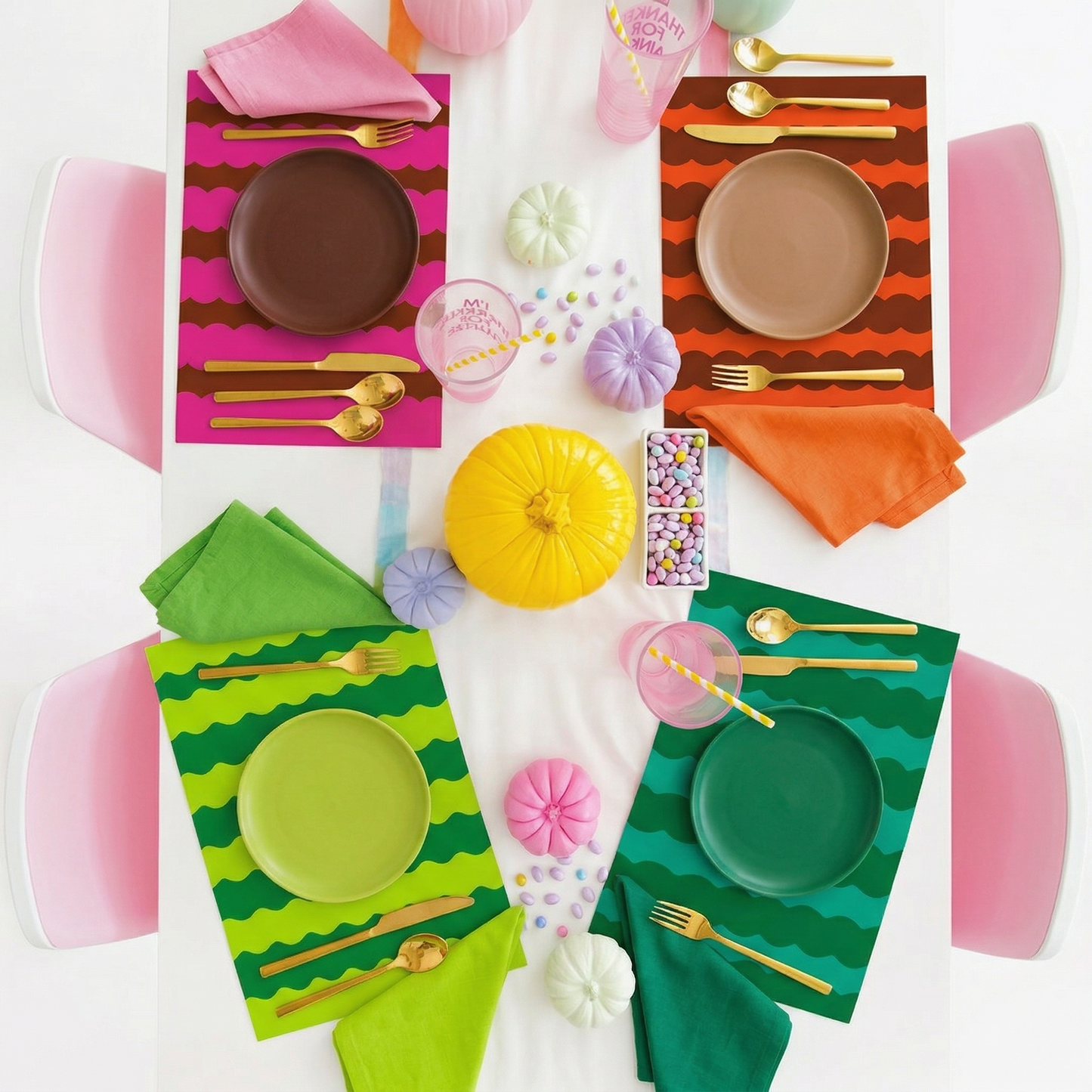 Colorful table setting with plates, napkins, and cutlery on striped paper placemats