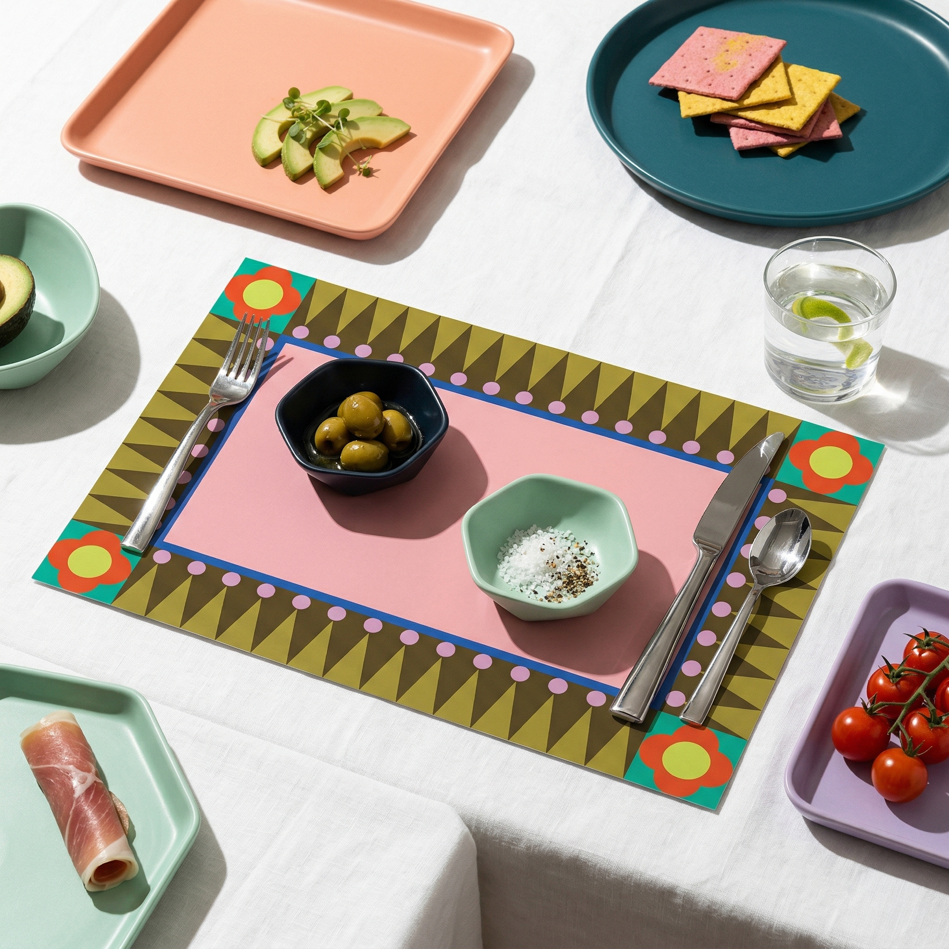 Colorful geometric paper placemat with food items on a white tablecloth