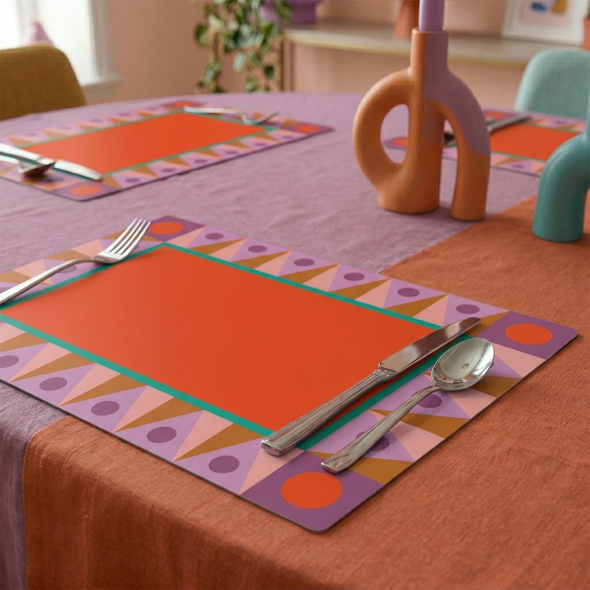 Colorful geometric patterned paper placemats on a white background