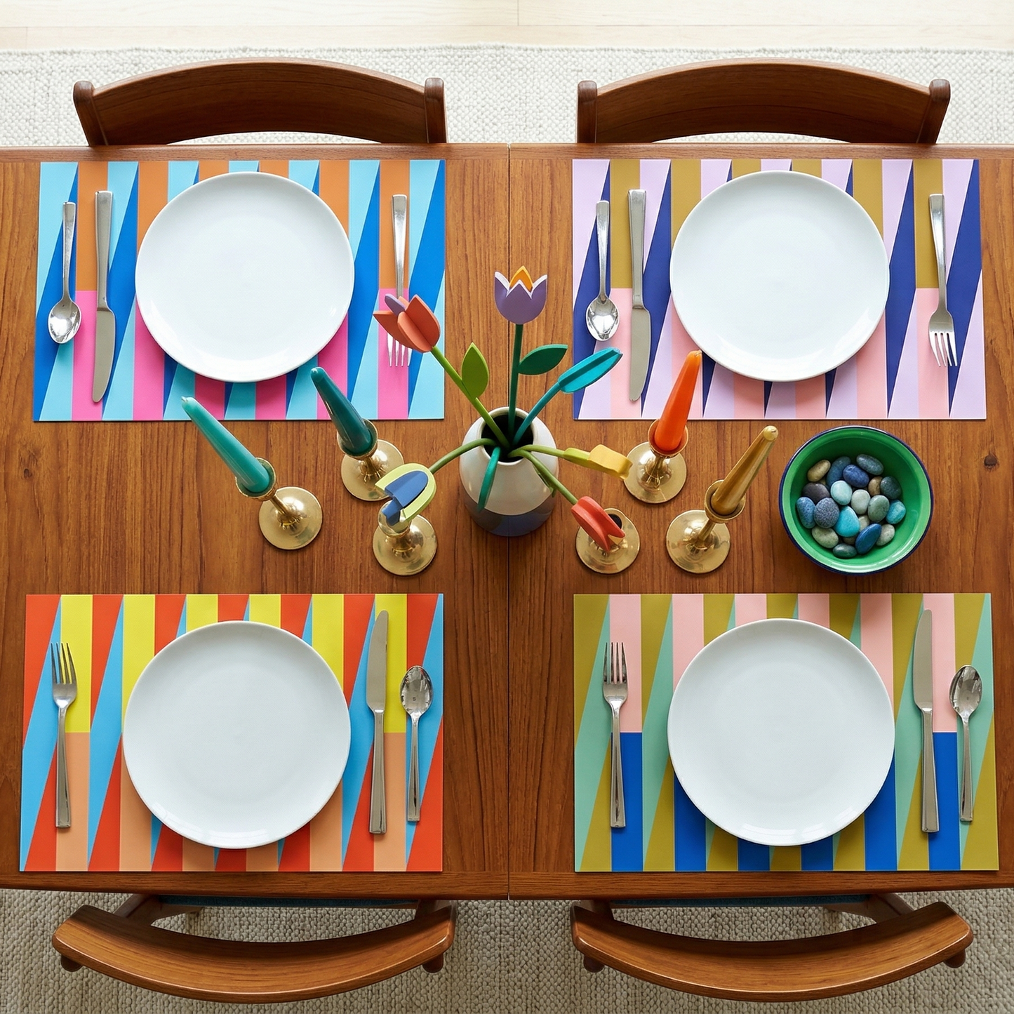 Dining table set with colorful paper placemats, plates, and cutlery on a wooden table.