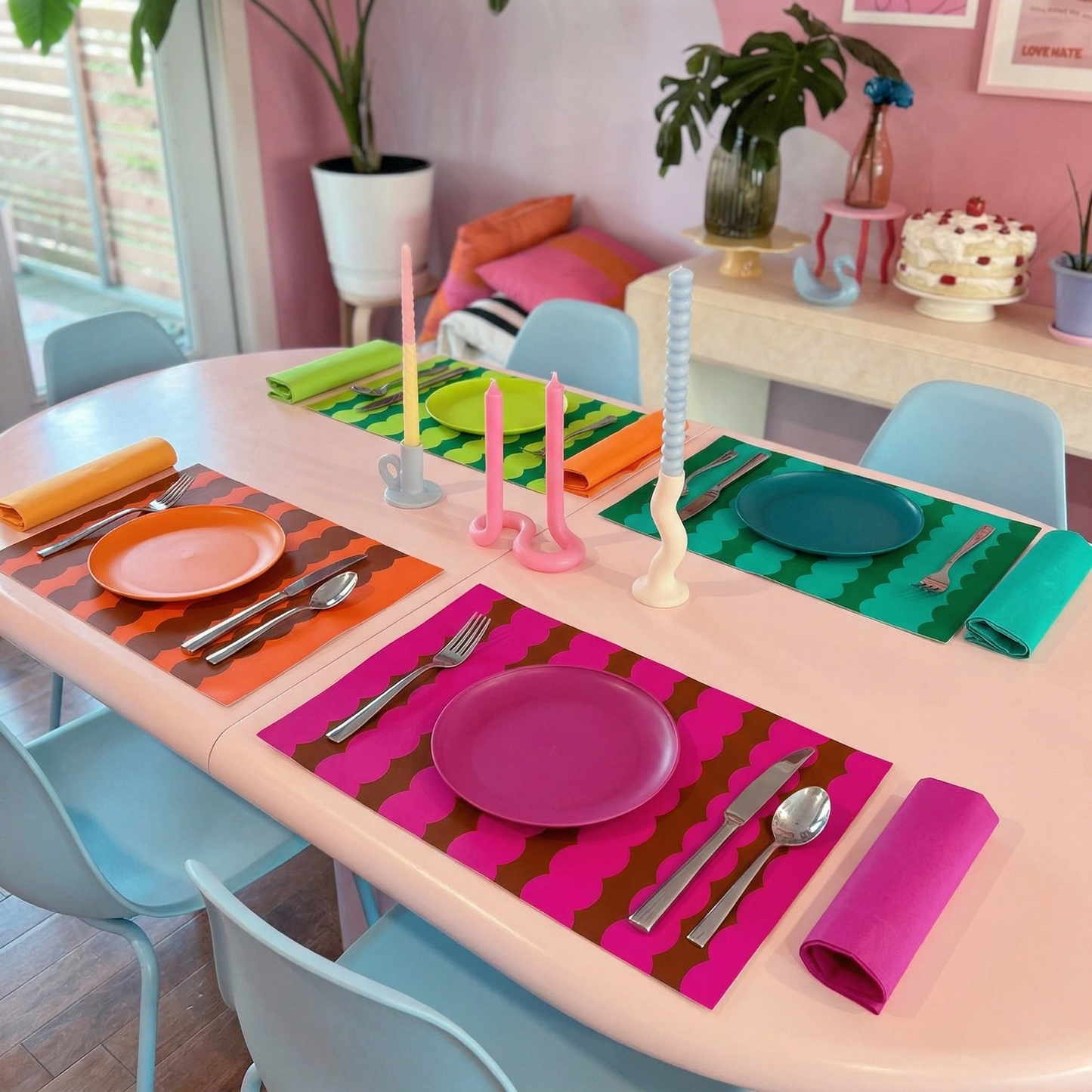 Colorful table setting with plates, cutlery, and paper placemats on a round table.