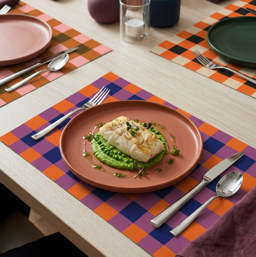 Plaid paper placemat on a table with dinner on a plate. 