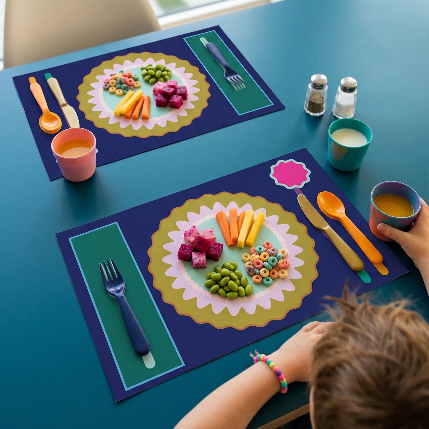 Children's placemats with colorful food illustrations on a blue table.