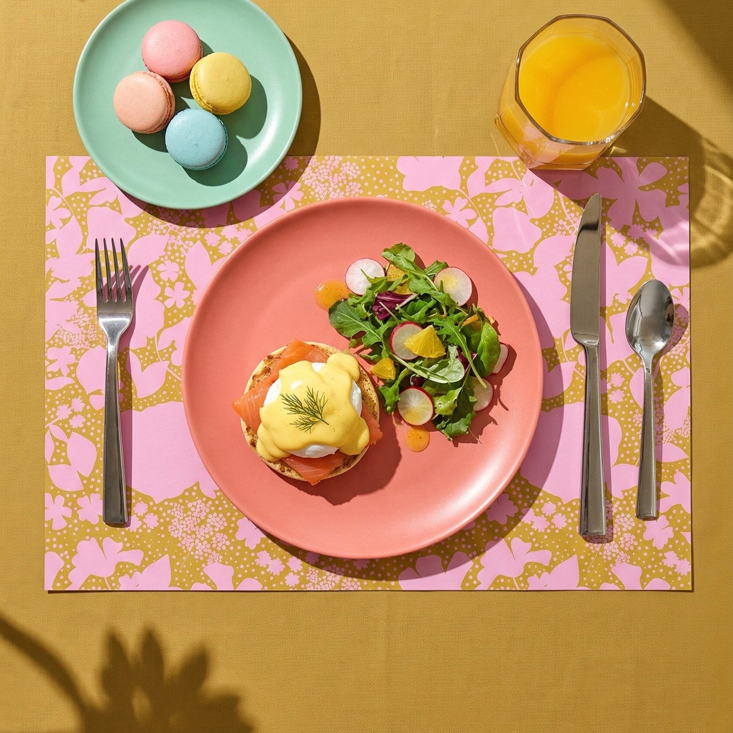 Floral-patterned paper placemat with cutlery on a white background