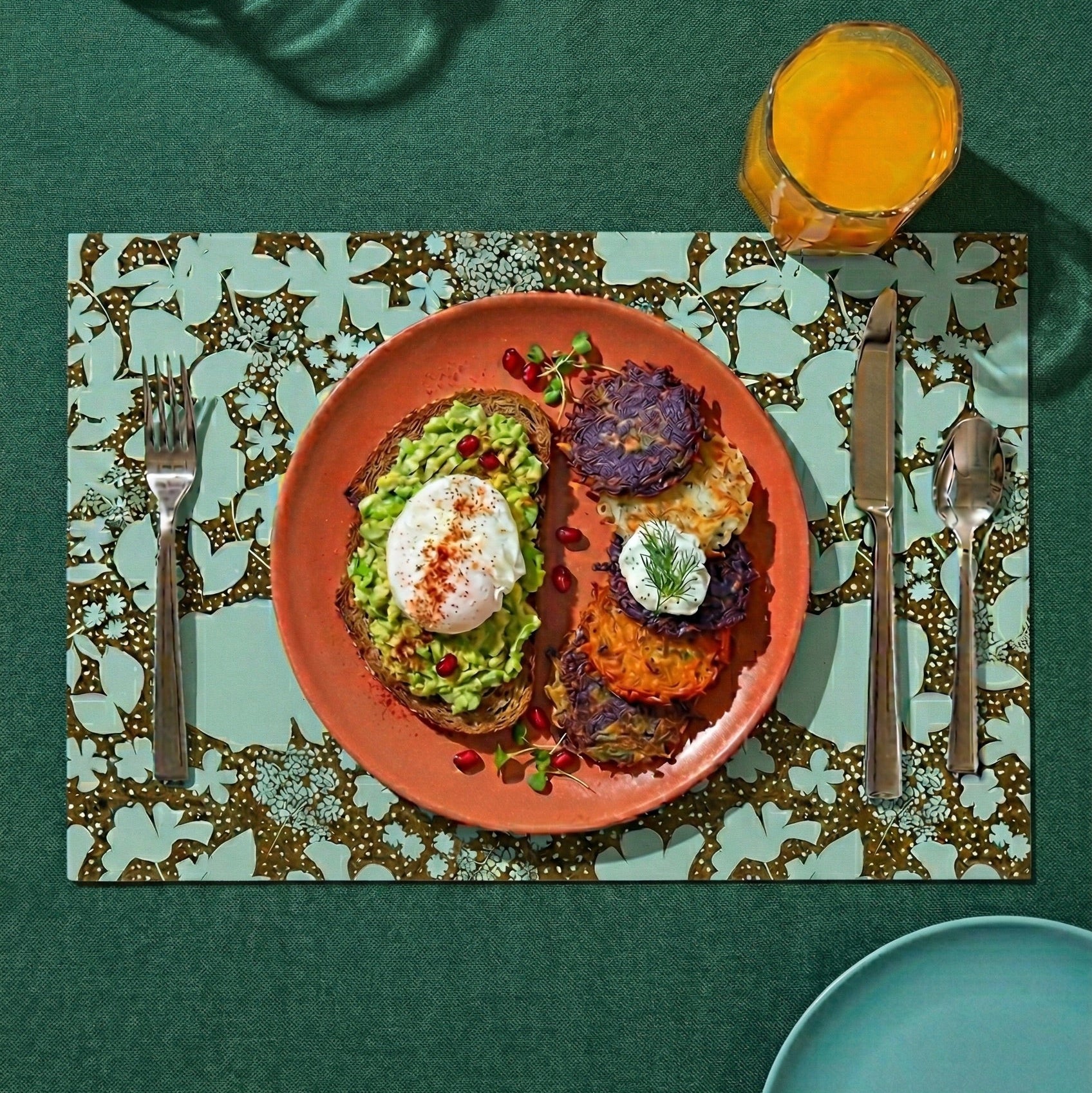 Floral-patterned paper placemat with cutlery on a green tablecloth