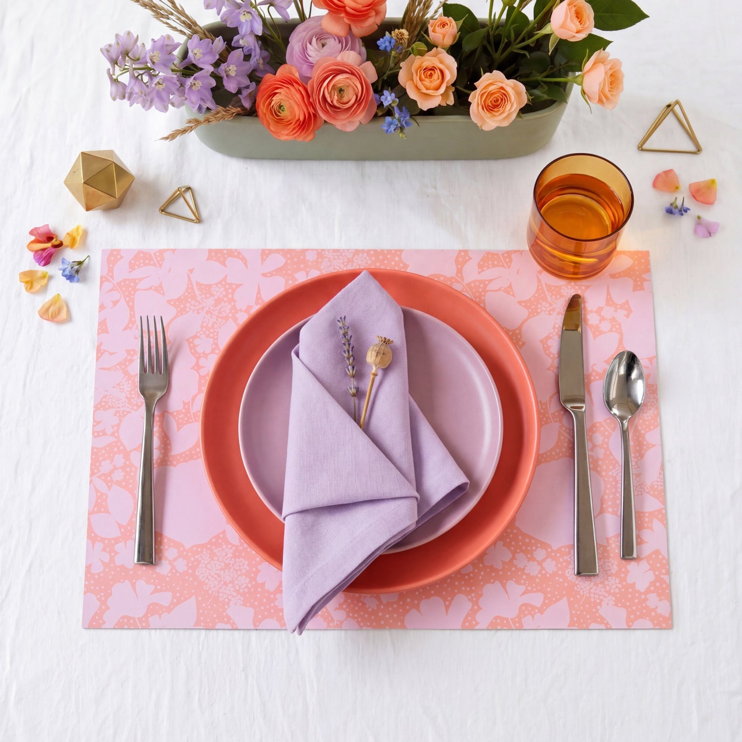Floral-patterned paper placemat with cutlery on a white background