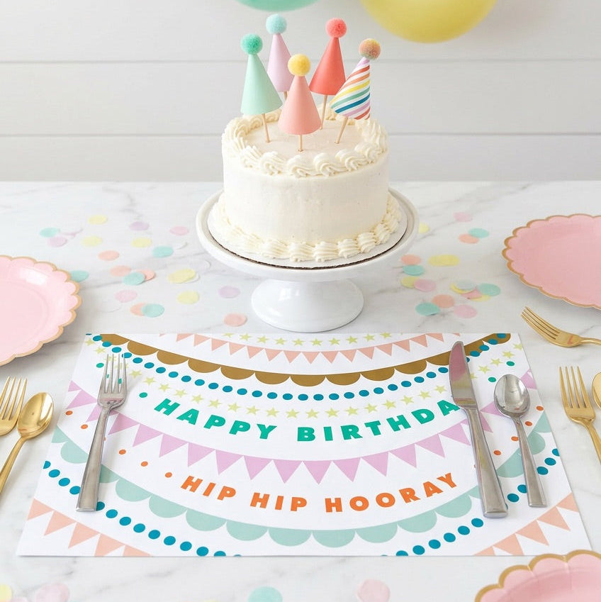 Birthday table setting with cake, balloons, and birthday paper placemat.
