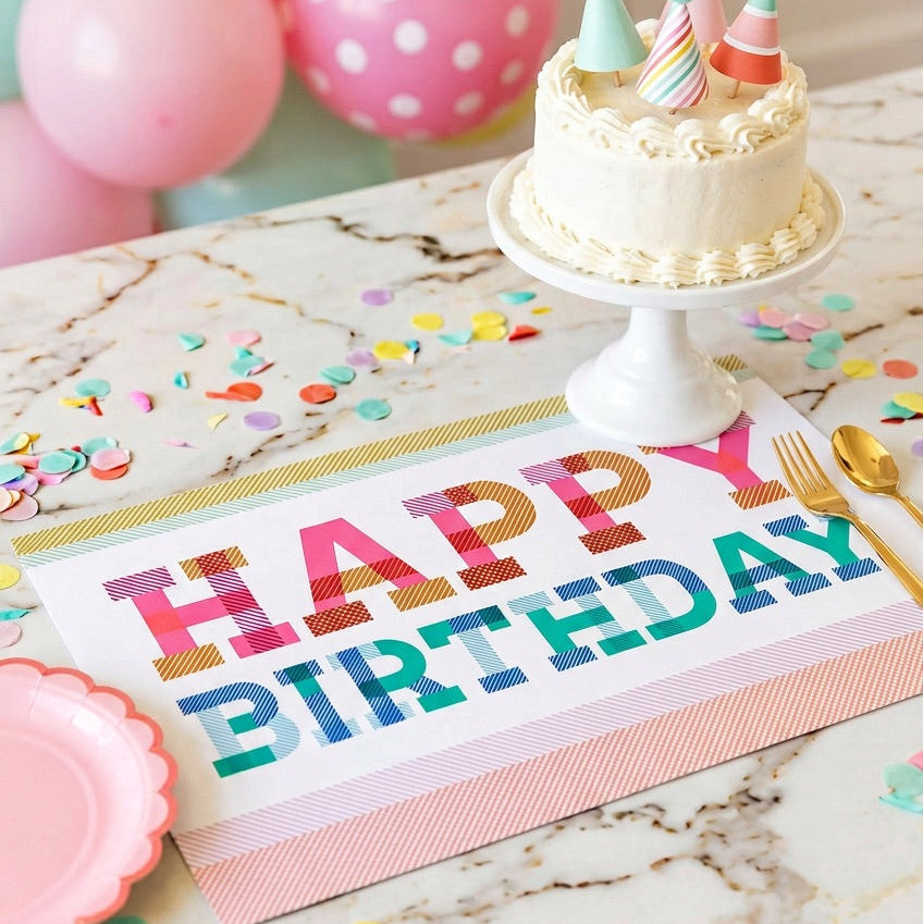 Happy birthday paper placemat on a table with a birthday cake. 