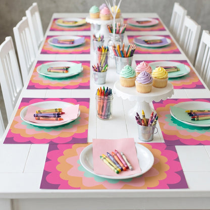 Children's birthday party setup with colorful balloons, cupcakes, crayons, and place settings paper placemats.