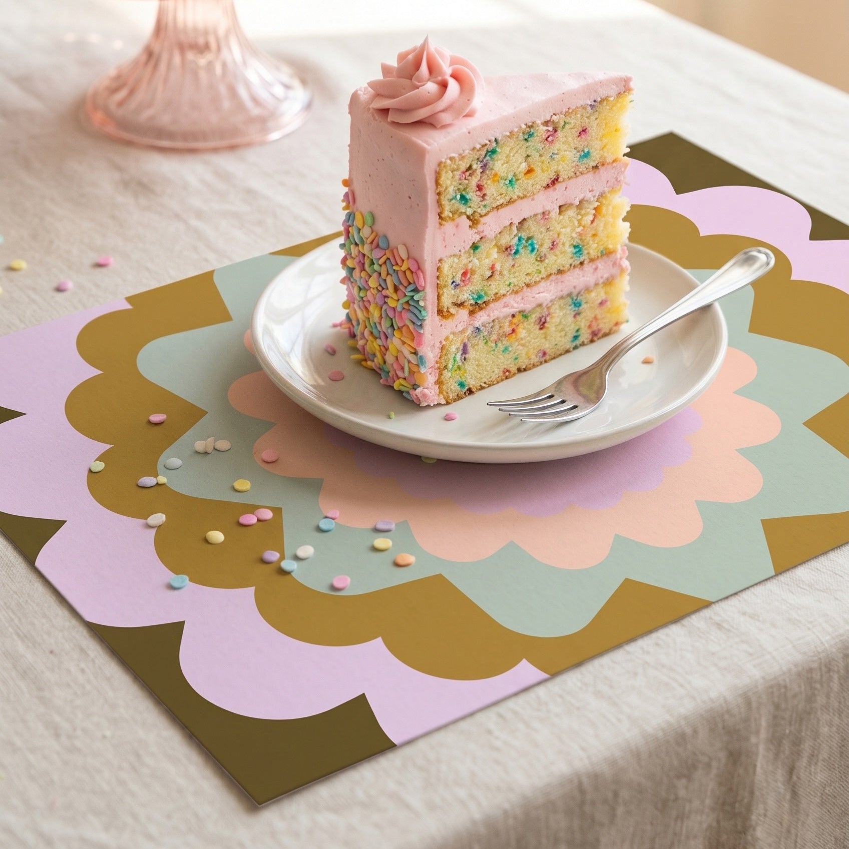 Pastel-colored layered cake with a slice on a plate on a decorative table mat.
