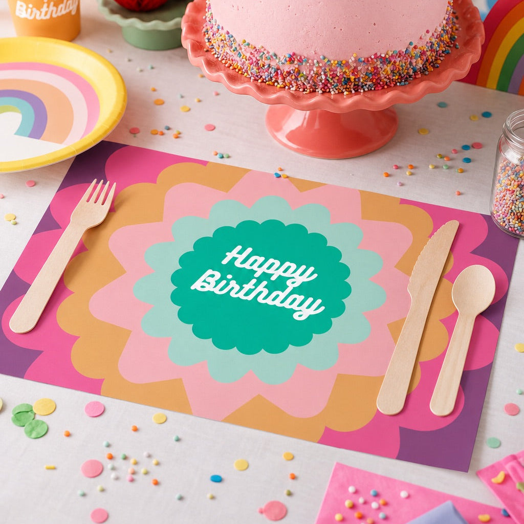 Birthday cake with colorful sprinkles on a paper placemat set with plates, cups, and utensils.