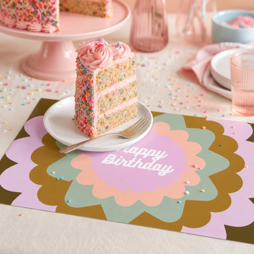 Birthday cake with a slice on a decorative paper placemat with 'Happy Birthday' text, surrounded by party decorations.