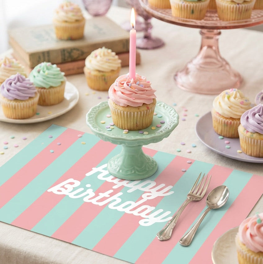 Birthday-themed table setting with cupcakes and a 'Happy Birthday' striped paper placemat.