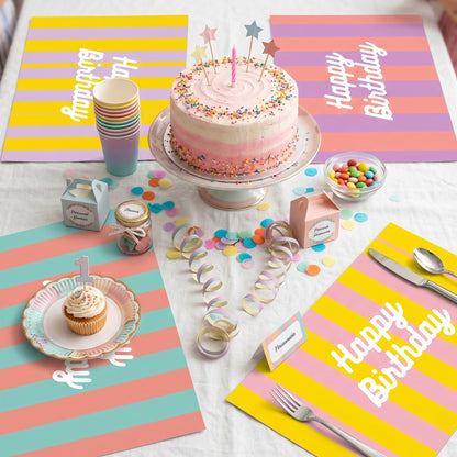Birthday table setting with a cake, plates, and colorful striped paper placemats.