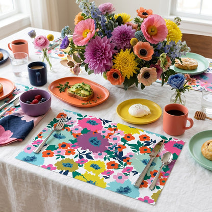 Colorful floral table setting with plates, cups, and a bouquet of flowers on floral paper placemats.