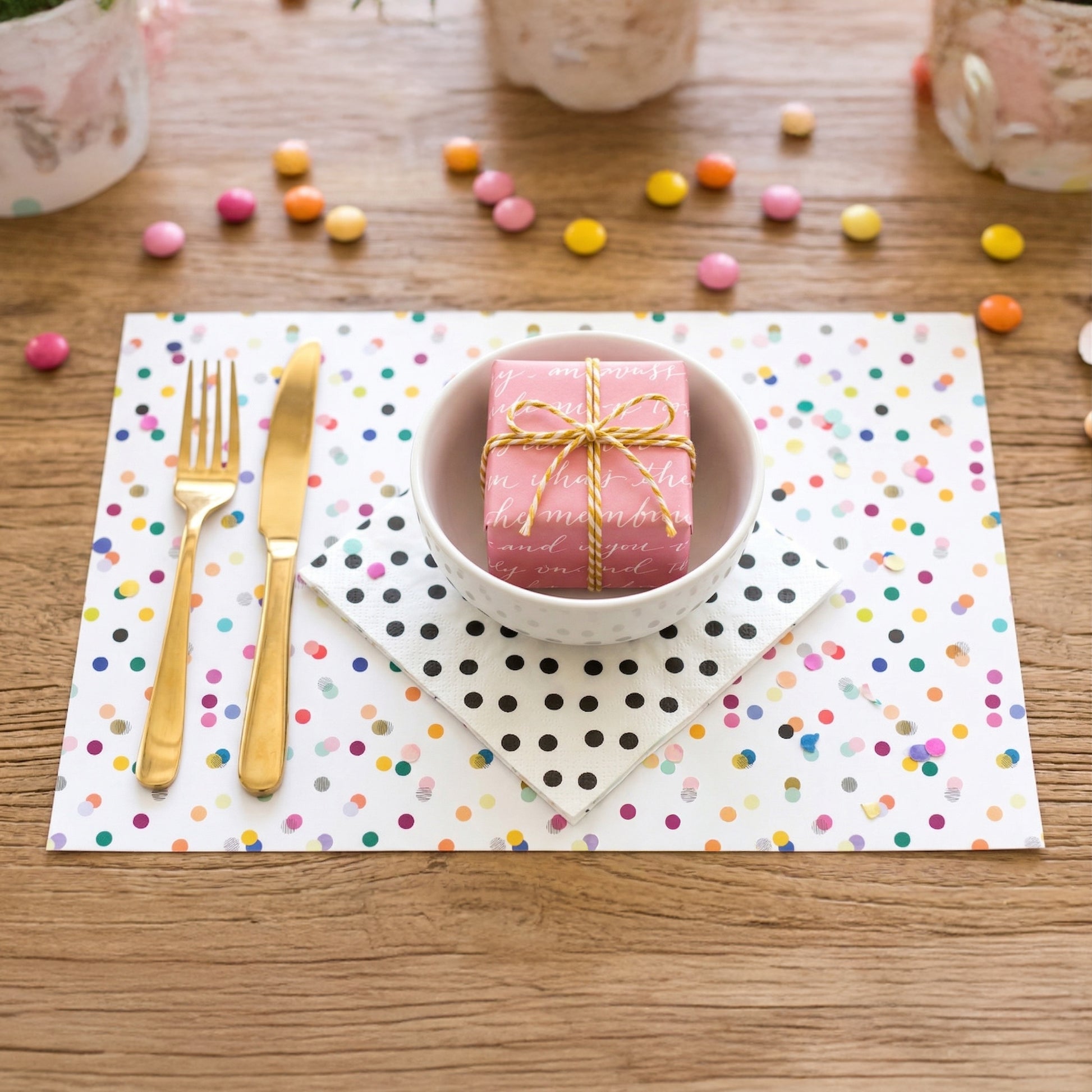 Confetti paper placemat with cutlery and a present on a table. 