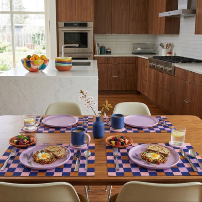 Kitchen with a dining table set for breakfast, featuring plates with food and paper placemats.