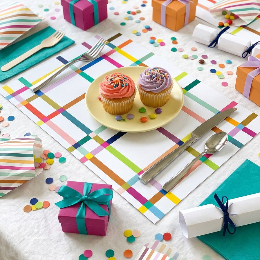 Colorful table setting with paper placemats, napkins, and small gifts on a white table.