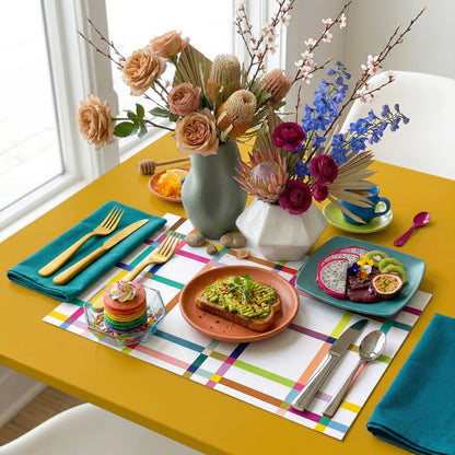 Colorful table setting with plates, cutlery, and flowers on a colorful paper placemat.